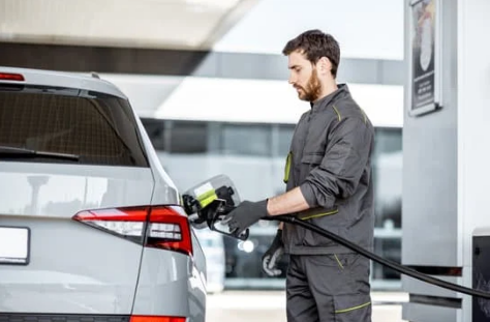 Worker at a gas station refueling a car.