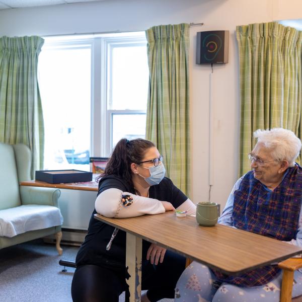 A health care worker talking to a resident in a care facility