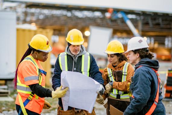 Construction workers with plan and hard hats